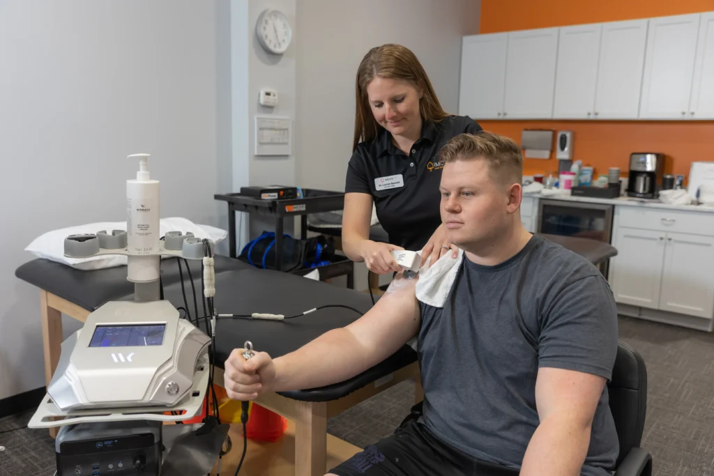 therapist at iMove Physical Therapy using Winback TECAR therapy to reduce pain in the patient's shoulder